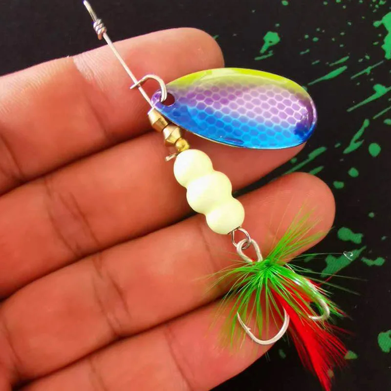 Una mano sosteniendo un señuelo de pesca. El señuelo consta de un anzuelo de metal con un cuerpo colorido e iridiscente que probablemente tiene una cualidad reflectante para atraer a los peces.