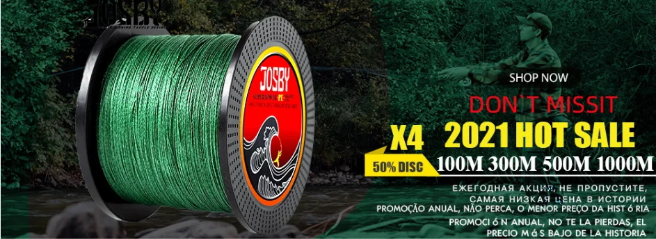 Un carrete de hilo de pescar de color verde con la marca JOSBY impresa. El carrete ocupa un lugar destacado en primer plano, con un fondo borroso que sugiere un entorno natural al aire libre, posiblemente un río o un lago, que es un entorno común para la pesca.