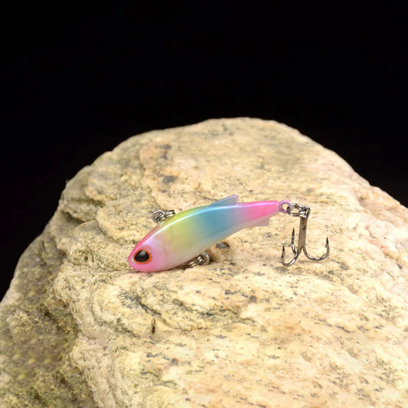 Señuelo de pesca colorido con tres ganchos que se muestran en una roca