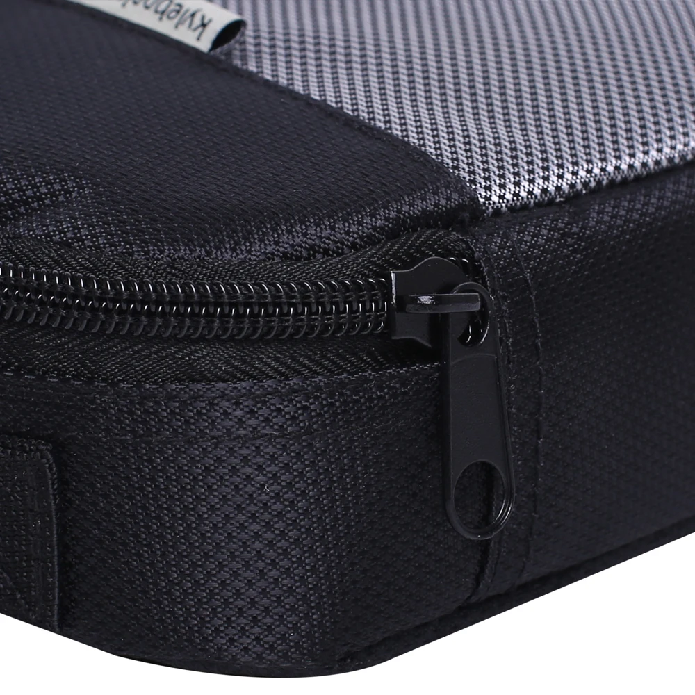 Un primer plano de un tirador de cremallera en una maleta. El tirador de la cremallera es una pieza de plástico negro con un lazo, que se utiliza para abrir y cerrar la cremallera.