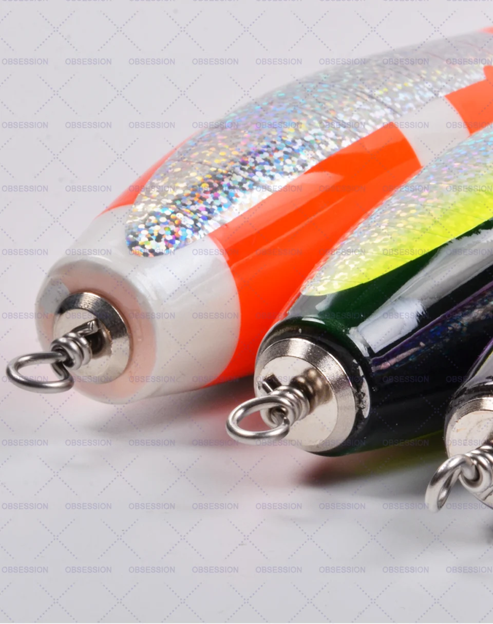 Dos señuelos de pesca. Están diseñados para parecerse a los peces y se utilizan para atraer peces cuando se pesca. Los señuelos tienen una superficie brillante y reflectante que imita las escamas de un pez y están equipados con anzuelos en la parte delantera y trasera para pescar.