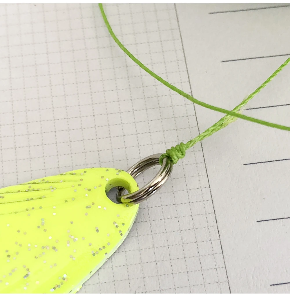 Un llavero con un diseño brillante de color amarillo brillante. El llavero tiene un anillo de metal adjunto y hay una cuerda o cordón verde atado alrededor del anillo.