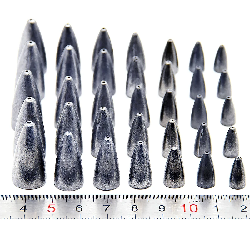 Un conjunto de púas o clavos metálicos de diferentes longitudes. Están dispuestos en una fila y hay una regla colocada junto a ellos para escalar.