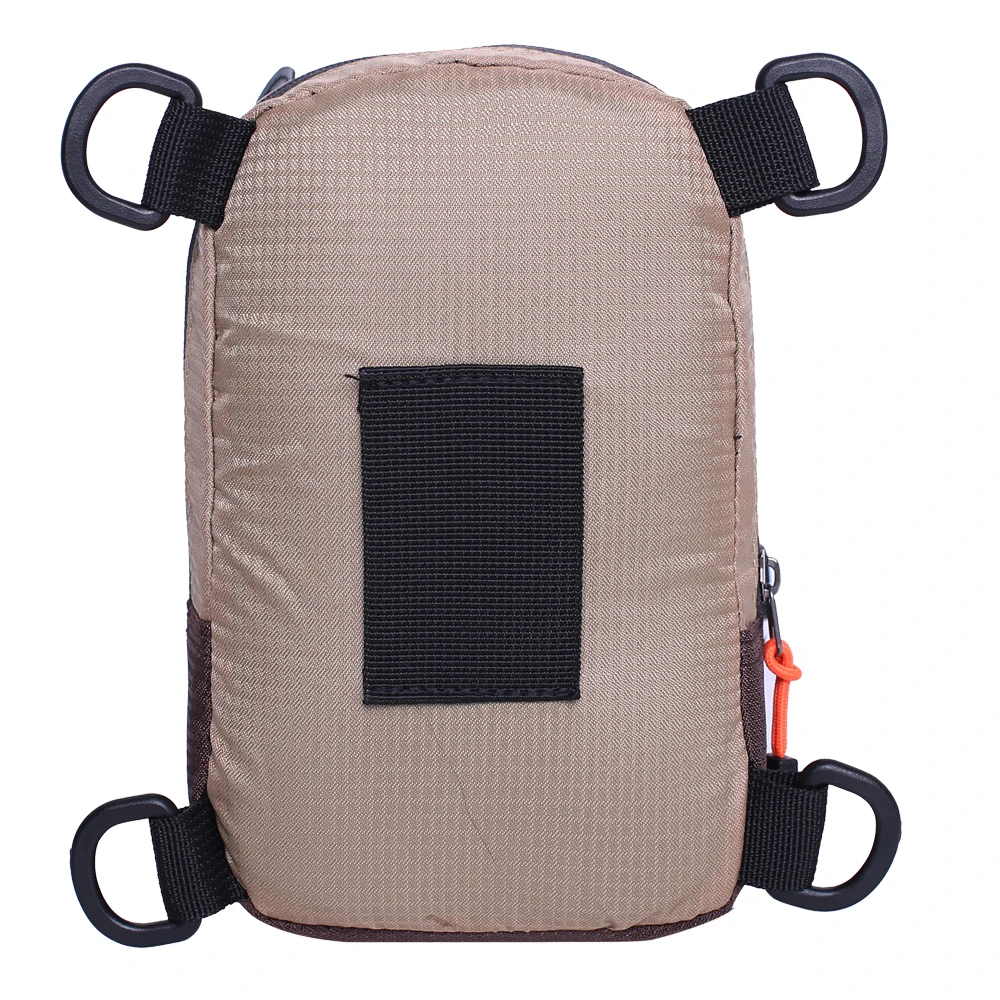 Una mochila con un diseño sencillo. Tiene un color beige o marrón claro con un panel negro en el frente, posiblemente para un logo o un parche. La mochila tiene correas negras con hebillas negras y un asa negra en la parte superior para llevar.