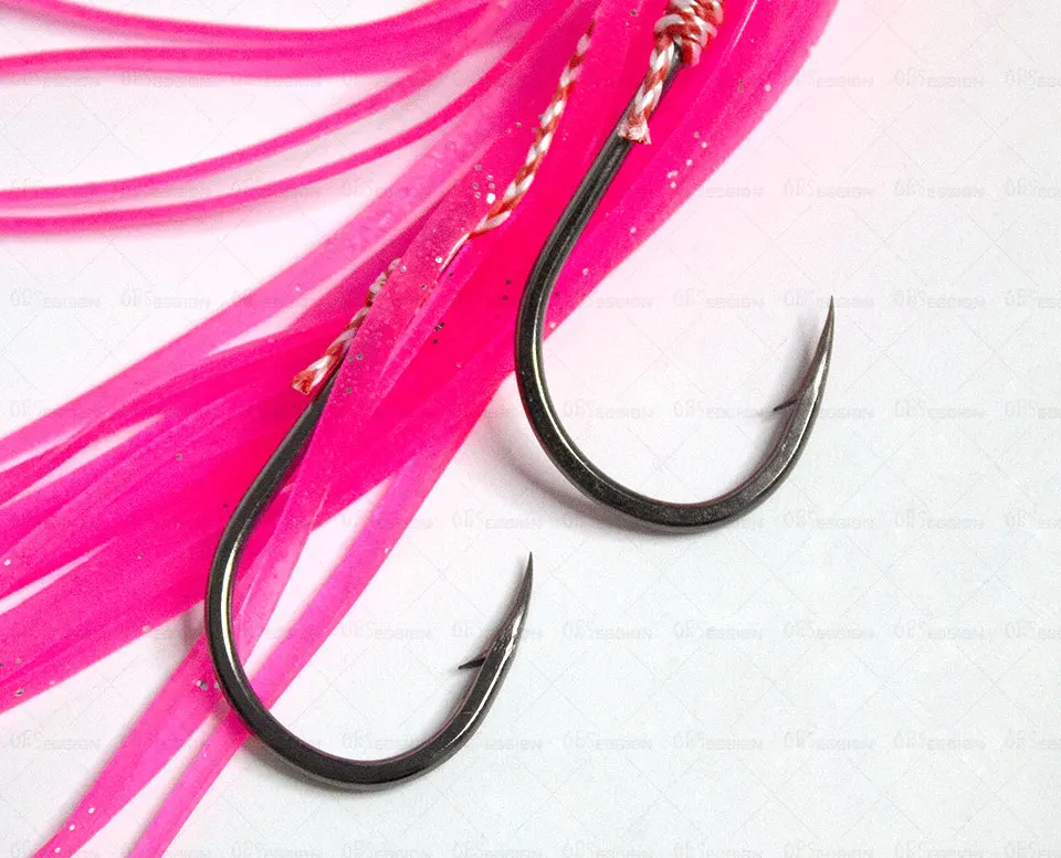 Un par de anzuelos de pesca con señuelos rosas adheridos. Los anzuelos están colocados de una manera que sugiere que están listos para usar, y los señuelos están diseñados para atraer peces.