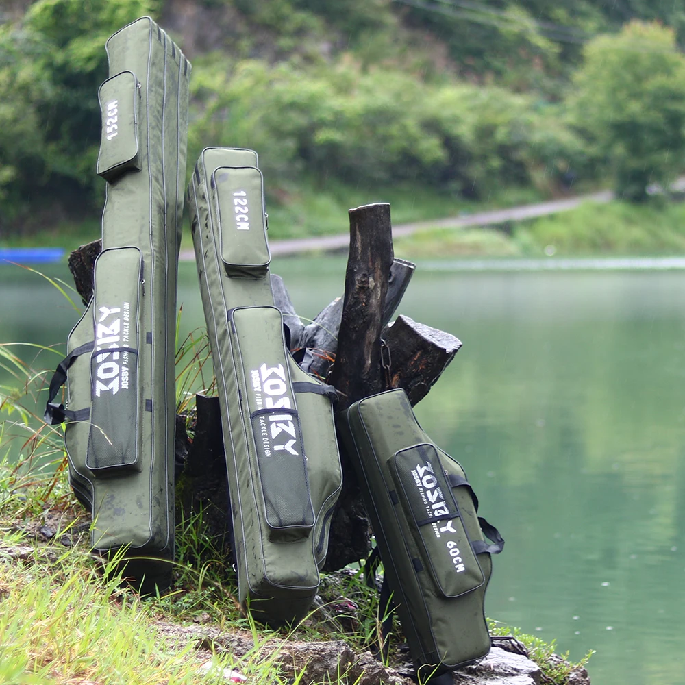 Una colección de estuches verdes para rifles o armas. Están apilados y apoyados contra un árbol o una estructura de madera, posiblemente en un entorno natural al aire libre. Los estuches tienen texto blanco, que podría ser el nombre de la marca o la información del modelo, pero no está claro desde este ángulo.
