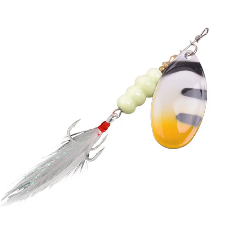 Un señuelo de pesca. Consiste en un gancho con una banda roja, un cuerpo de plástico transparente con un patrón amarillo y negro y una serie de pequeñas cuentas redondas de color verde.