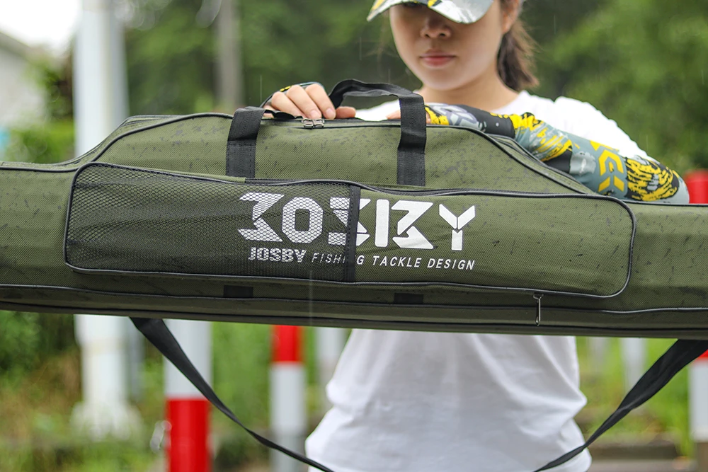 Una persona que sostiene un estuche grande, verde y acolchado con el texto 30X30 y JOSBY FISHING TACKLE DESIGN impreso. El estuche parece estar diseñado para transportar aparejos de pesca, como lo indica la marca.