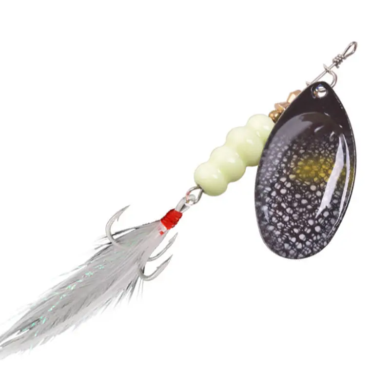 Un señuelo de pesca. Consiste en un cuerpo negro y amarillo, una cuenta verde, un anzuelo plateado y una hoja plateada que probablemente vibra cuando el señuelo está en movimiento para atraer peces.