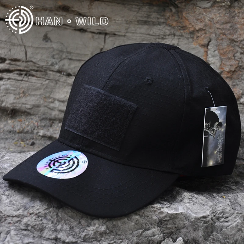 Una gorra de béisbol negra con ala plana. En el frente de la gorra, hay un logo circular con un diseño que parece ser una letra H estilizada dentro de un círculo.