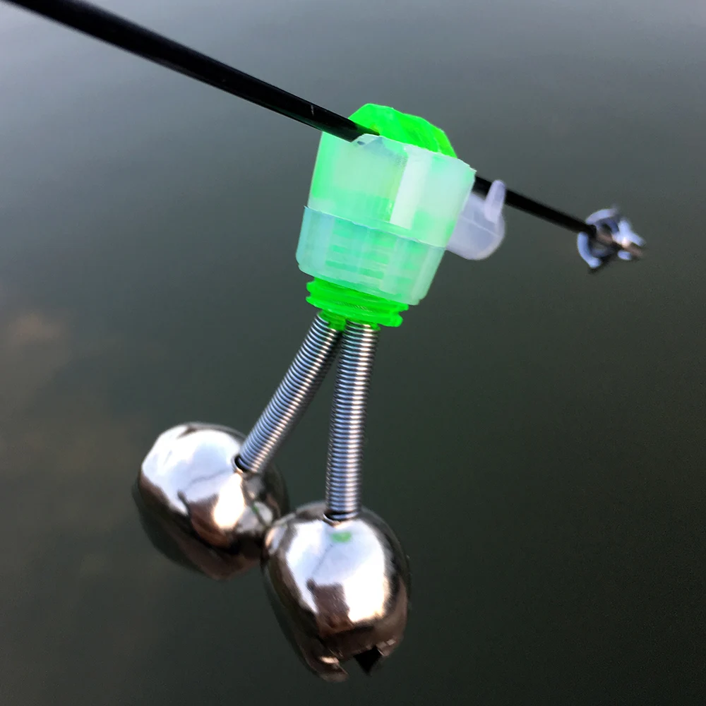 Un señuelo de pesca. Consiste en un cuerpo de plástico verde, un anzuelo de metal y un par de bolas de metal plateadas que probablemente se usan para pesar y para crear un sonido de traqueteo cuando el señuelo se mueve a través del agua.