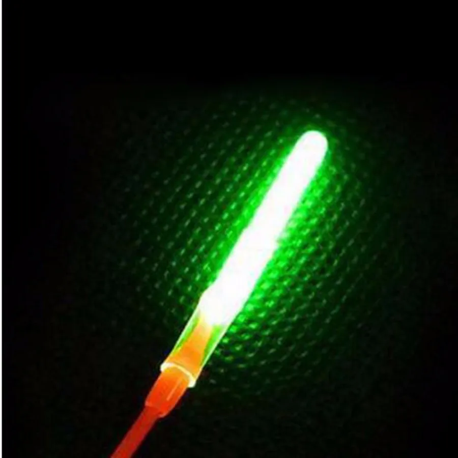 Un sable de luz verde con mango rojo. Parece ser un juguete o un accesorio diseñado para parecerse a un sable de luz de la franquicia Star Wars. El sable láser está iluminado, la luz verde emana de la hoja y el mango rojo proporciona un color contrastante.