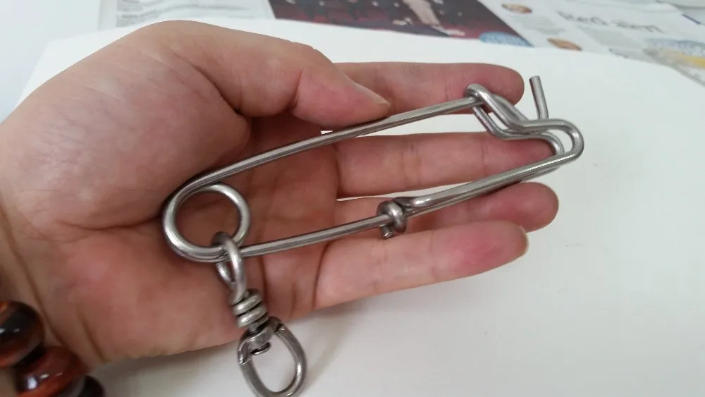 Una mano que sostiene un pequeño objeto metálico que parece ser un llavero o un tipo de accesorio similar.