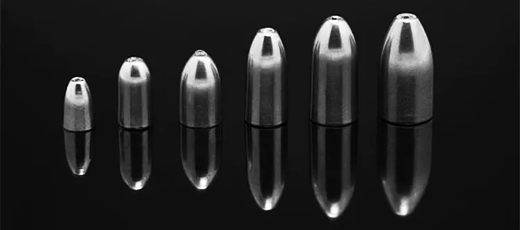 Una gama de objetos metálicos en forma de bala que varían en tamaño, que se muestran contra un fondo negro reflectante