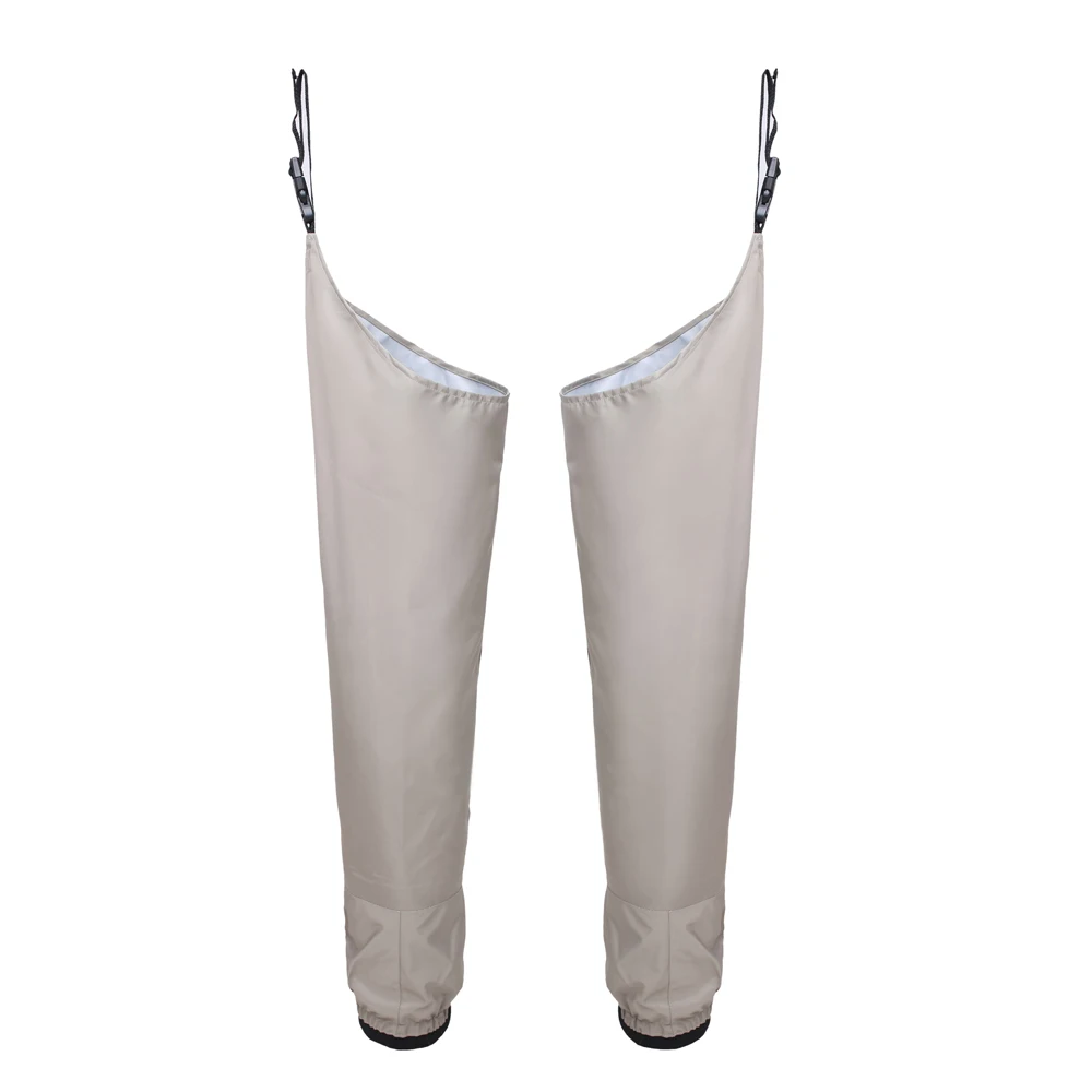 Un par de pantalones de lluvia beige. Están diseñados para usarse sobre pantalones normales para proteger al usuario de la lluvia y las condiciones húmedas. Tienen cremallera en la parte delantera para cierre y elástico en cintura y tobillos para un ajuste ceñido.