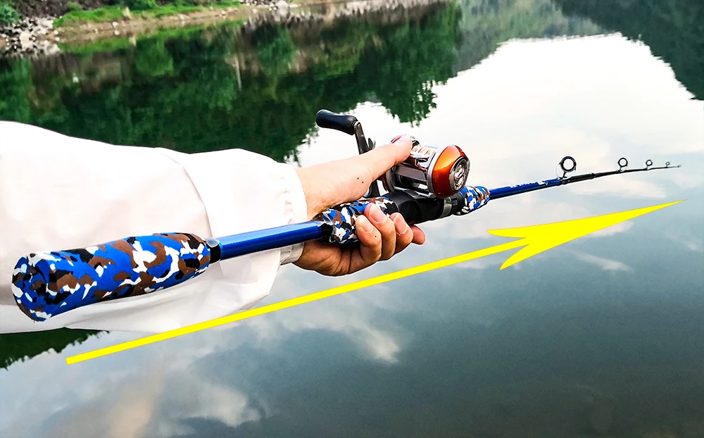 Una persona que sostiene una caña de pescar con un carrete adjunto. La caña tiene un patrón de camuflaje en el mango y el carrete es una combinación de rojo y negro.
