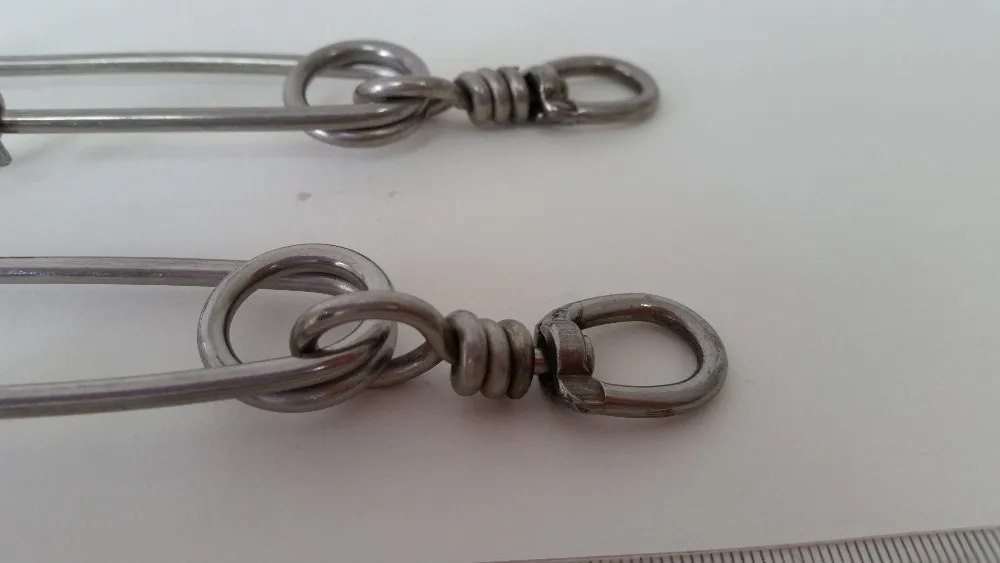 Un par de ganchos de metal de color plateado, que parecen mosquetones. Por lo general, se utilizan para asegurar artículos a la presilla del cinturón, la mochila u otras superficies similares. Tienen una puerta con resorte que permite abrirlos y cerrarlos.