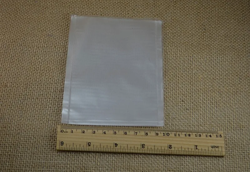 Se coloca una lámina de plástico transparente al lado de una regla de madera sobre un fondo de tela texturizada