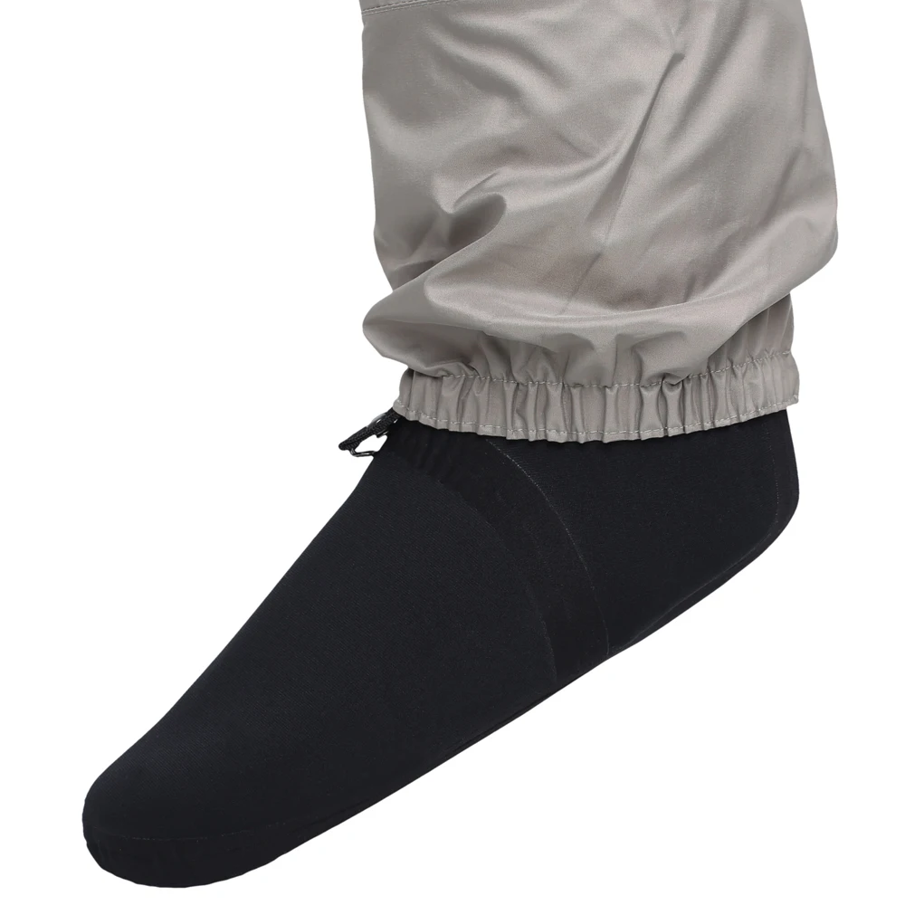 Una sola pierna de una persona que lleva un par de calcetines negros y unas mallas o prendas de compresión grises. Los calcetines parecen tener un largo estándar y las mallas se levantan justo debajo de la rodilla.