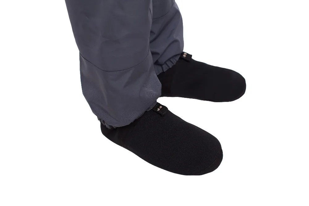 Una persona que vestía calcetines negros y pantalón gris. Los calcetines parecen estar un poco sueltos alrededor de los tobillos y la persona está de pie con los pies ligeramente separados. El fondo es liso y blanco, lo que sugiere que podría ser una foto de producto destinada a mostrar los calcetines.