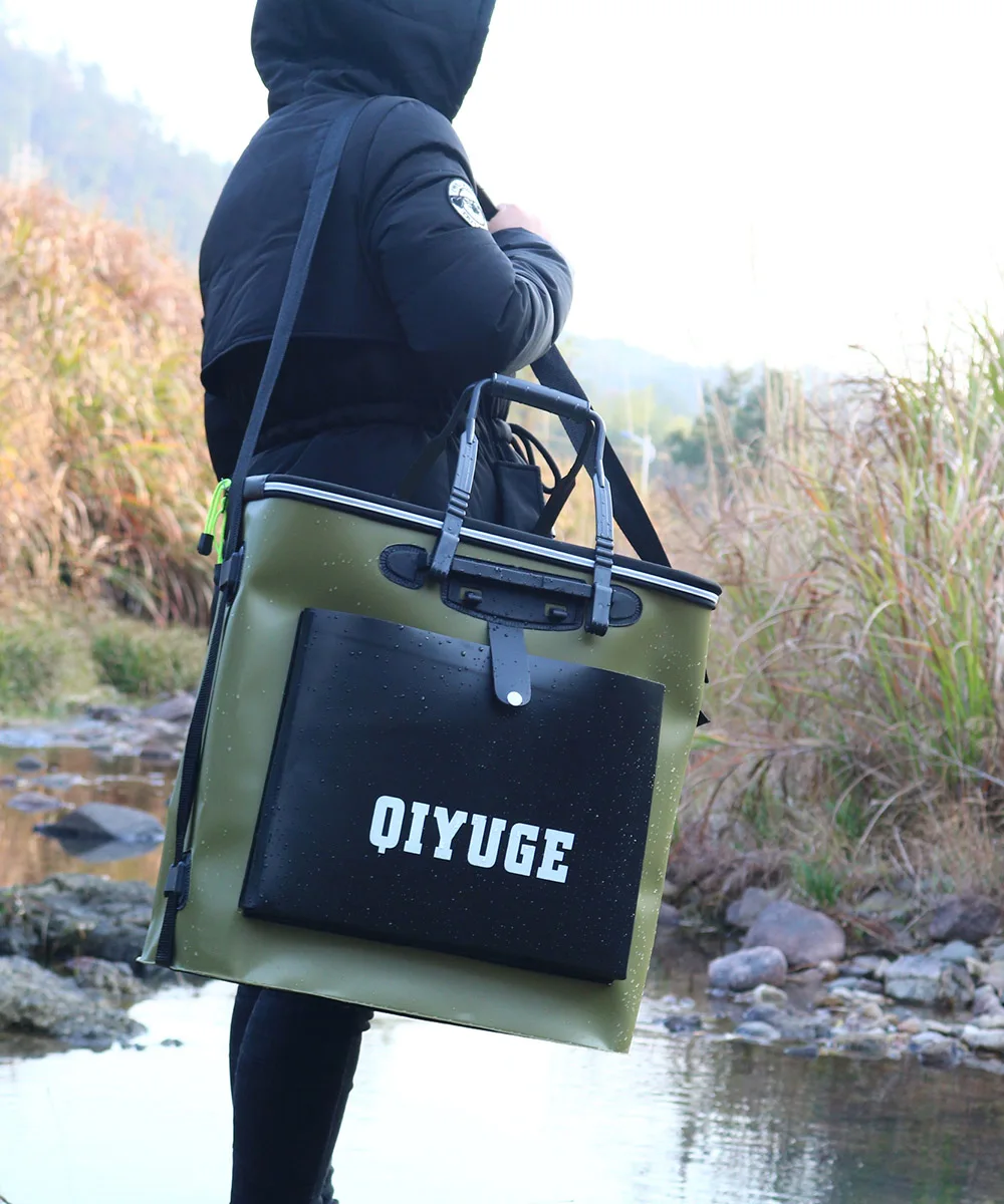 Una persona parada cerca de una masa de agua, posiblemente un río o arroyo, con una mochila. La mochila es verde oliva con una solapa negra que tiene impresa la palabra Oiyuge.