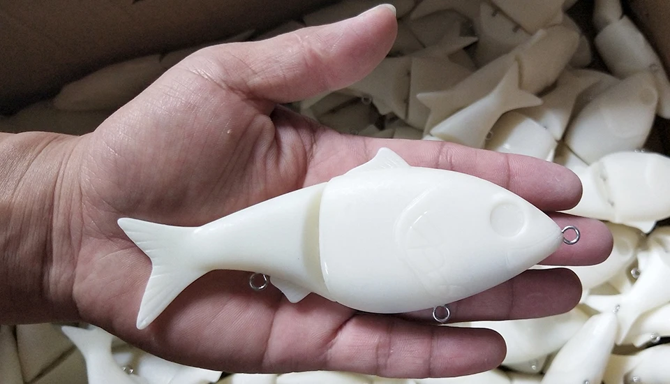 Un objeto de plástico blanco en forma de pez con dos bucles de metal para el accesorio