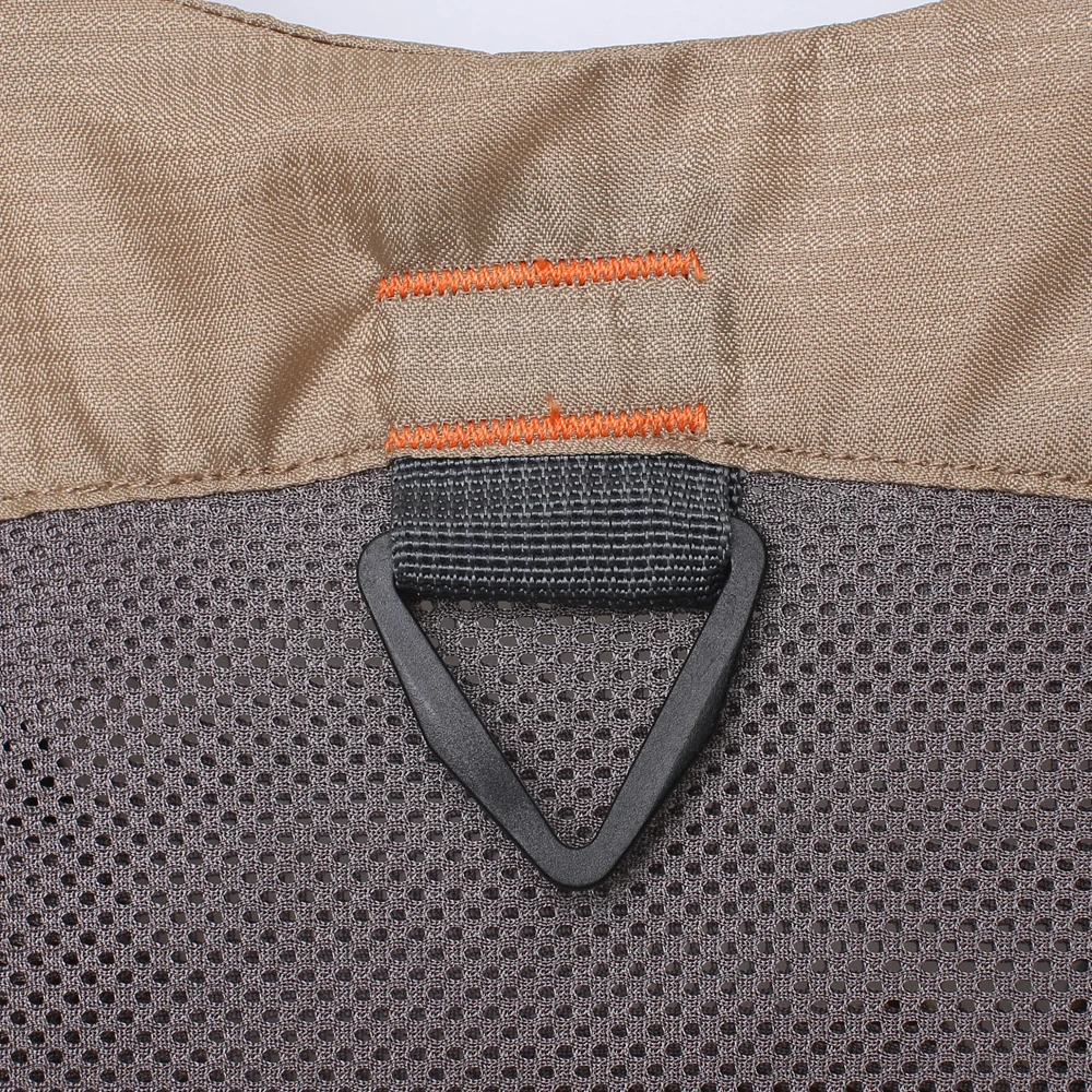 Un primer plano de una tela con un patrón texturizado. Hay una costura visible con un hilo naranja contrastante y un objeto negro de forma triangular adherido a la tela. La tela parece ser un tipo de malla o un material con un patrón en forma de cuadrícula.