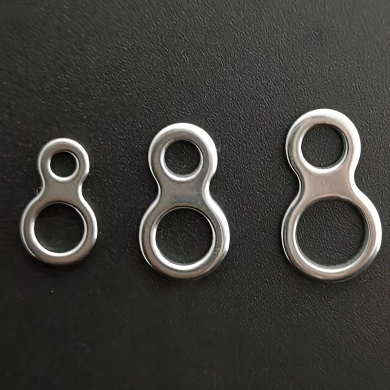 Tres anillas de metal, que parecen llaveros o anillas similares. Se colocan sobre una superficie oscura y cada anillo tiene un orificio por el que se podría introducir una llave o un objeto similar.