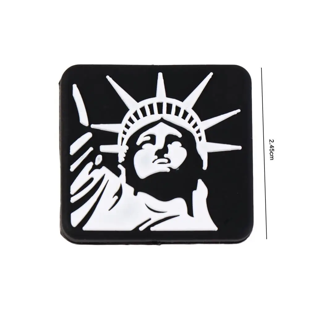 Un objeto de forma cuadrada con fondo negro y una representación blanca de una figura simbólica que mide 2