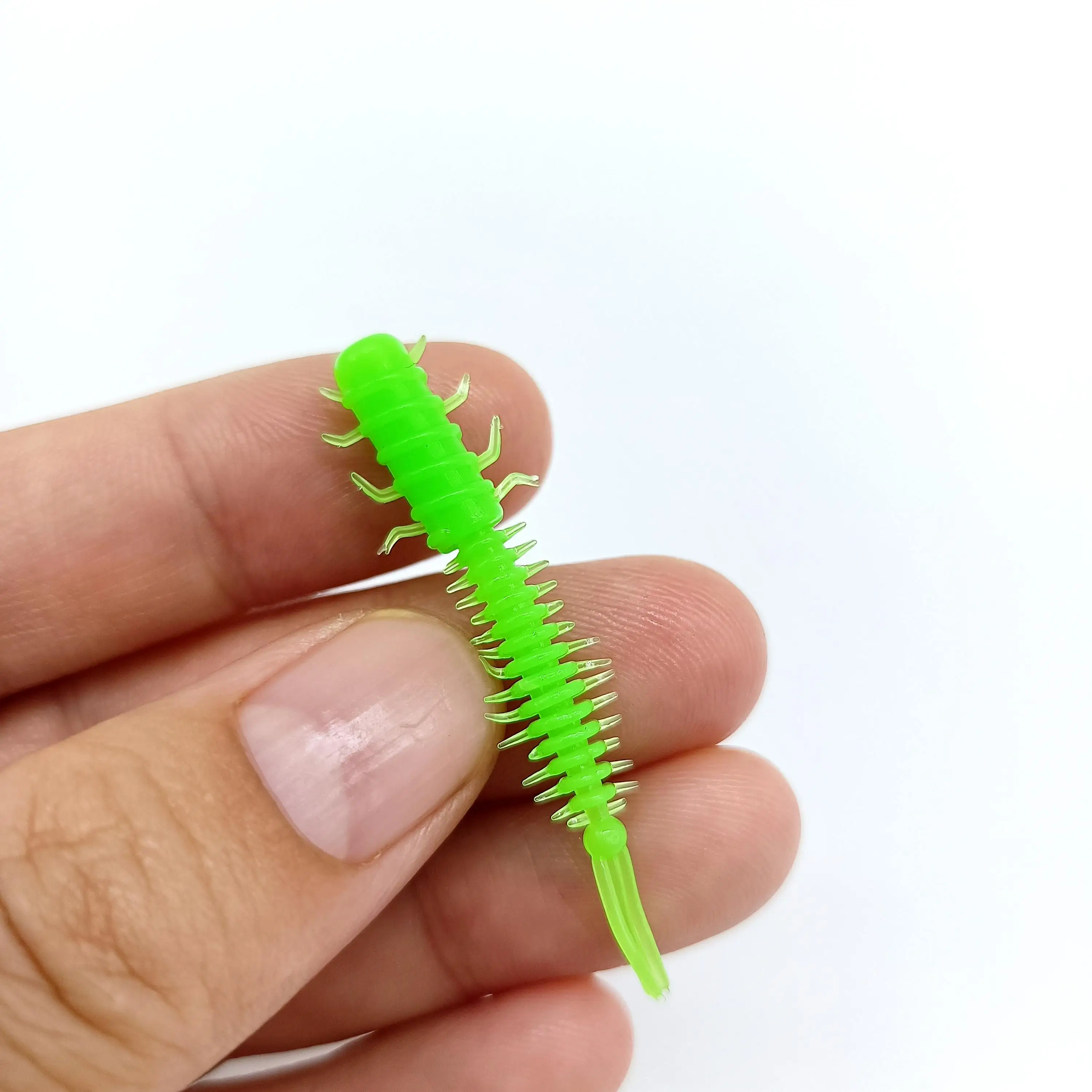 Un pequeño modelo de plástico verde vibrante de un ciempiés descansa delicadamente en el dedo de una persona, mostrando detalles intrincados y artesanía