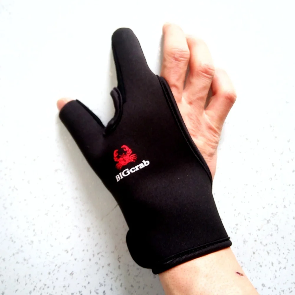 La mano de una persona que lleva un guante negro con un logo rojo distintivo en la parte posterior. El logotipo parece ser un cangrejo estilizado y el texto BIGG es visible, lo que sugiere que el guante podría ser un producto de una marca con ese nombre.
