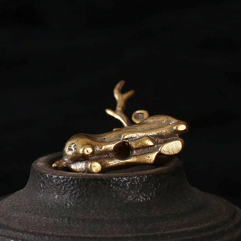 Una escultura dorada bellamente elaborada descansa sobre una base oscura texturizada, exudando elegancia y arte