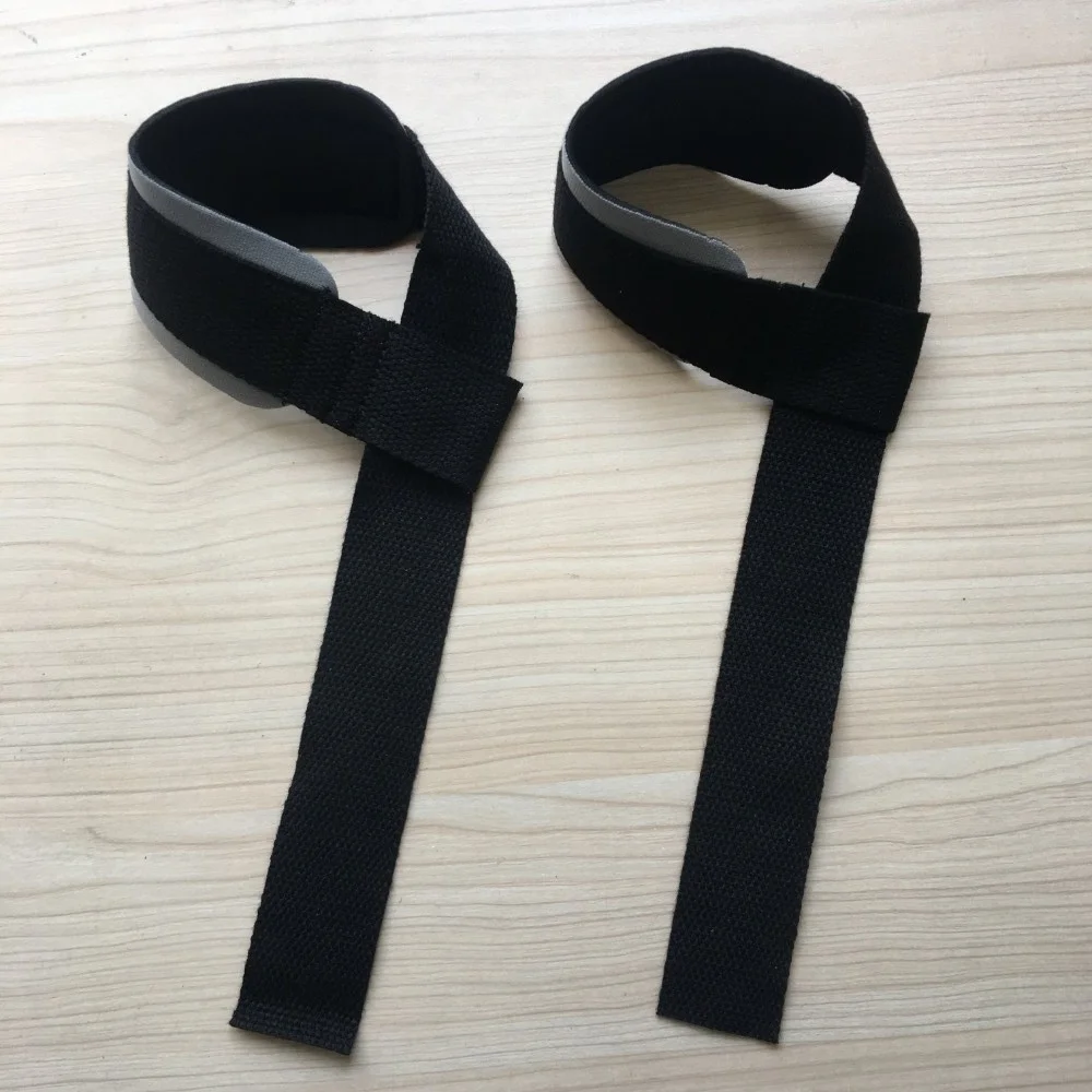 Un par de correas negras con hebillas, que parecen ser parte de un arnés o algún tipo de equipo que requiere correas ajustables. Se colocan planos sobre una superficie de madera.