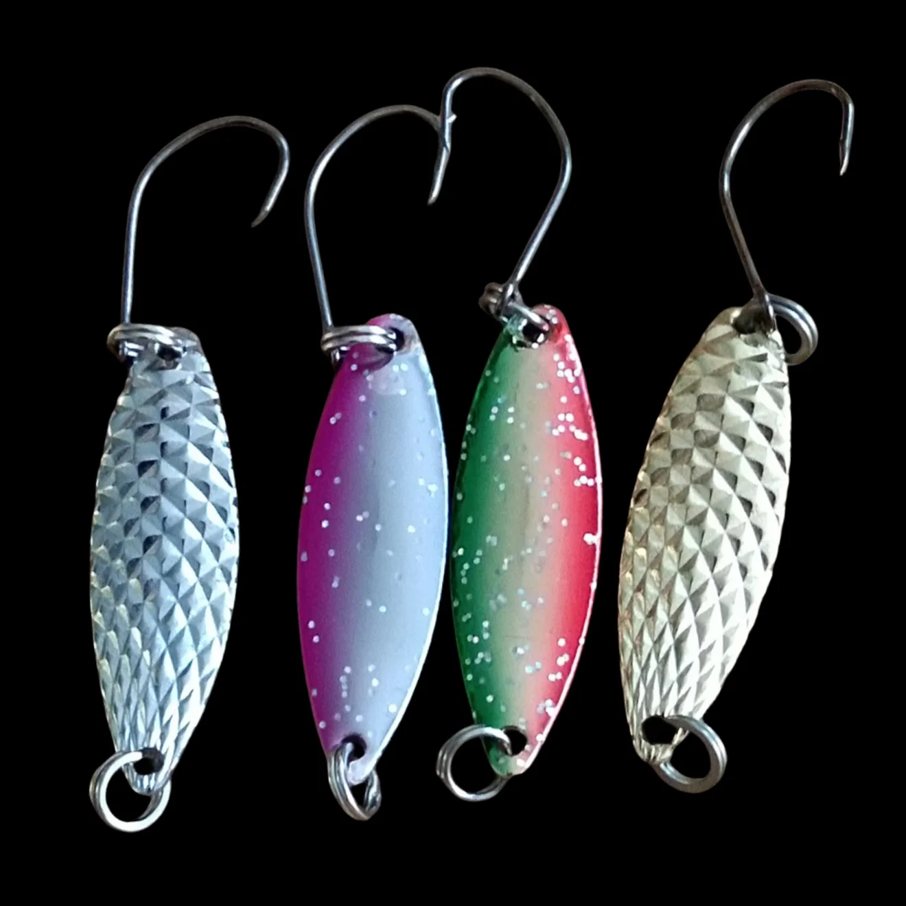 Tres ganchos de pescado con señuelos coloridos colgando de ellos