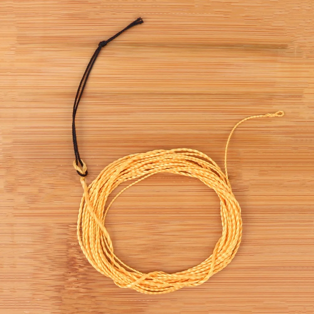 Una bola amarilla de hilo está en una mesa de madera