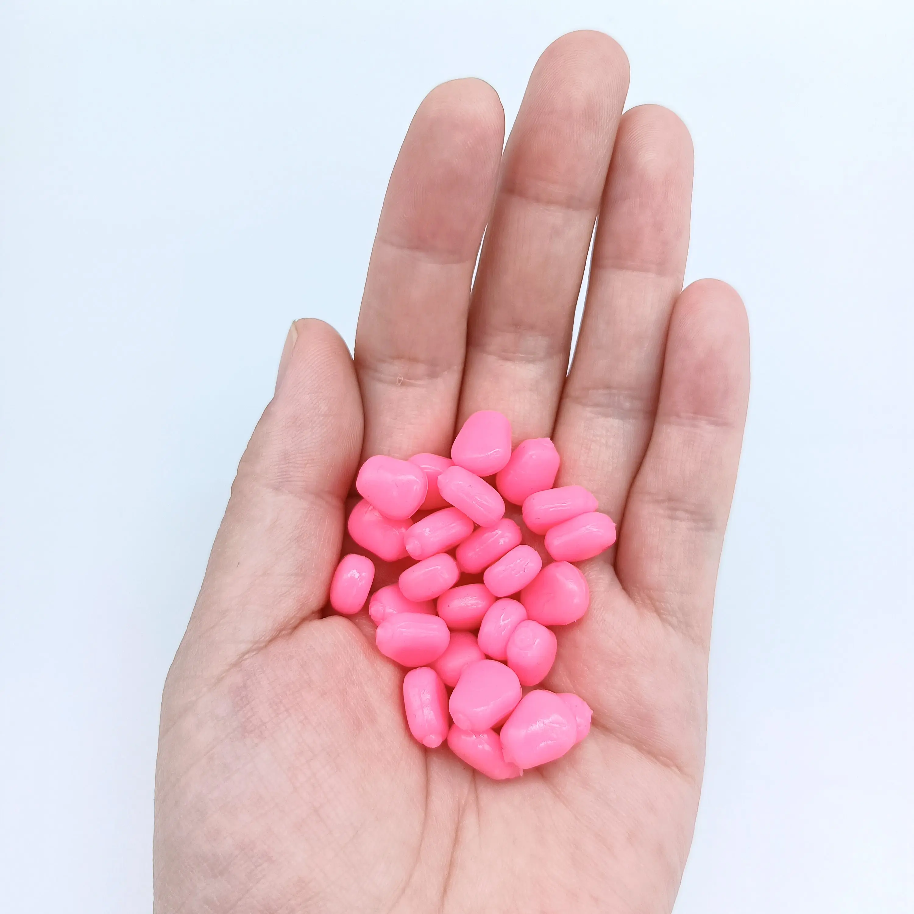 Una mano acuna suavemente una colección de dulces rosados ​​en forma de corazón que simboliza el amor y la dulzura