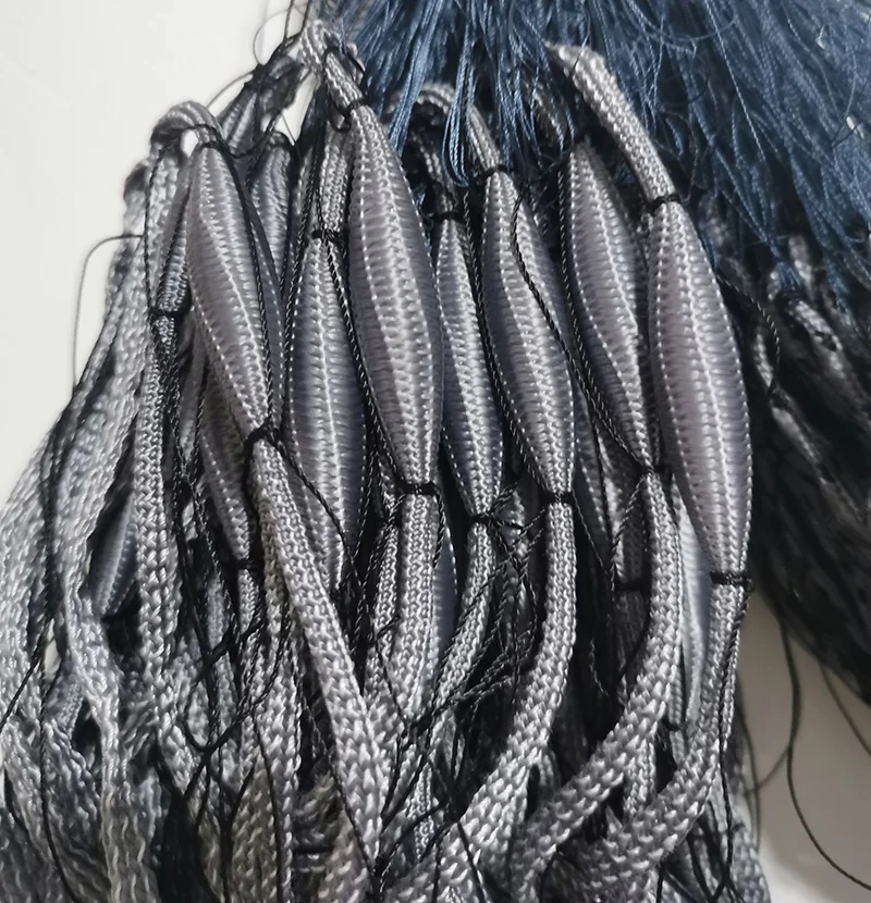 Cordones grises y negros intrincadamente tejidos, probablemente utilizados para elaboración o fines decorativos