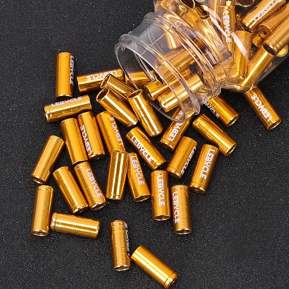 Componentes cilíndricos dorados con marca 'léble' dispersada en una superficie oscura