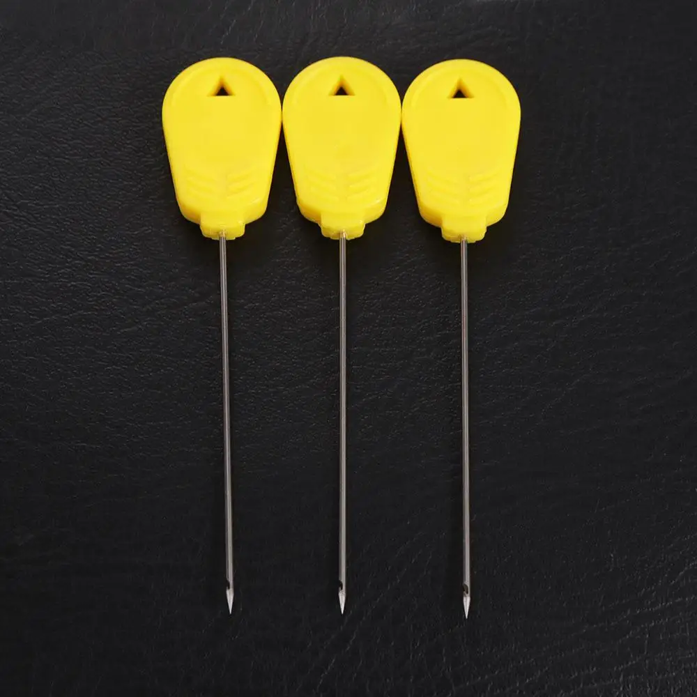 Se muestran tres agujas de mango amarillo sobre un fondo negro
