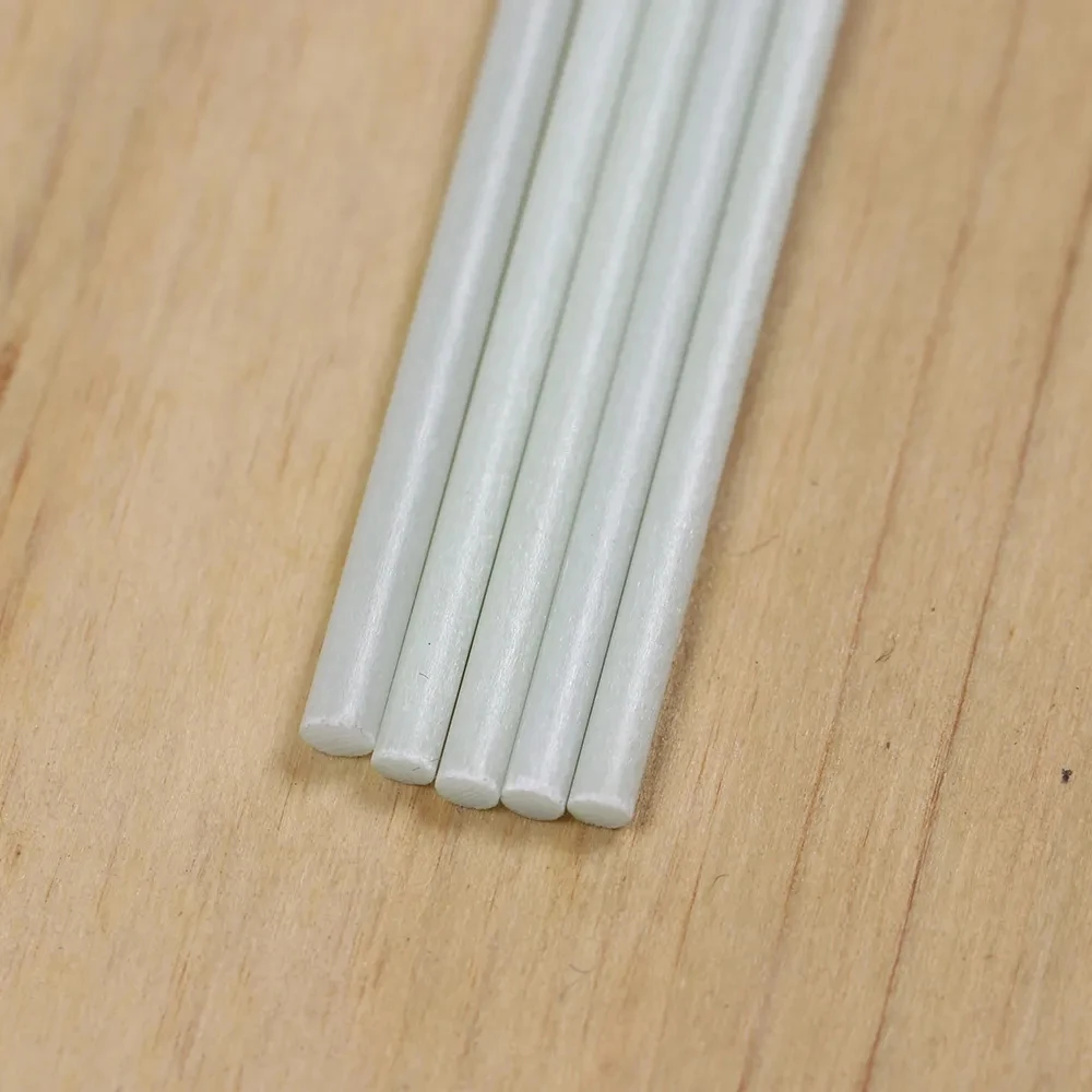 Cinco varillas blancas lisas están perfectamente alineadas en una superficie de madera