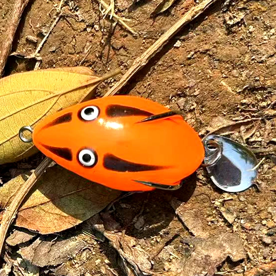 Un vibrante señuelo de pesca de naranja con una cola de ruleta metálica brillante perfecta para atrapar peces en entornos naturales