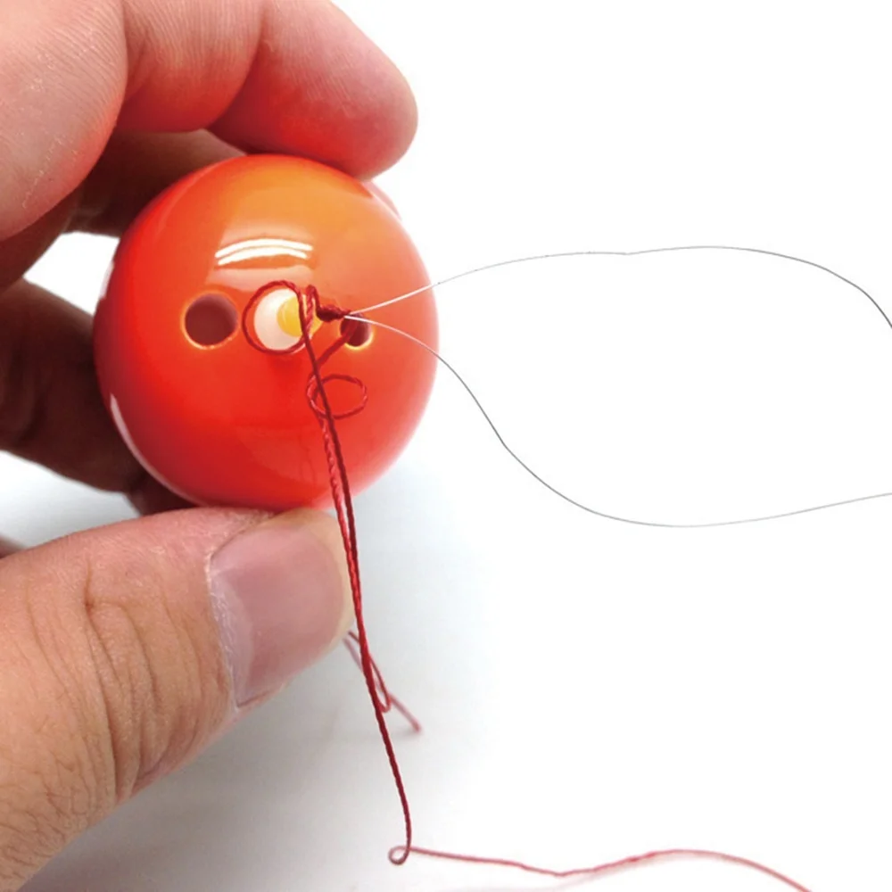Una persona que sostiene un objeto pequeño de color naranja que parece ser una pelota con una cuerda atada