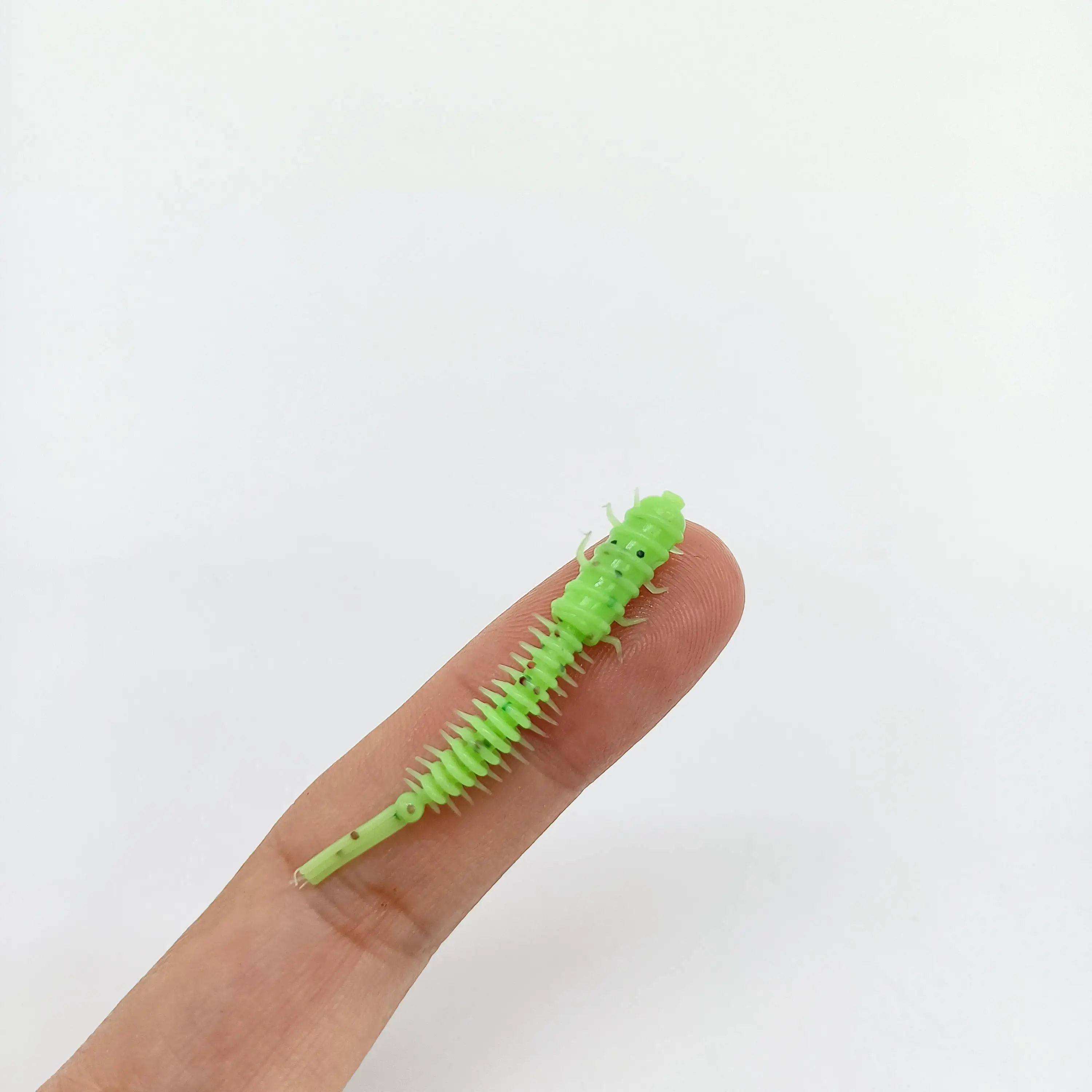 Pequeña oruga verde en el dedo