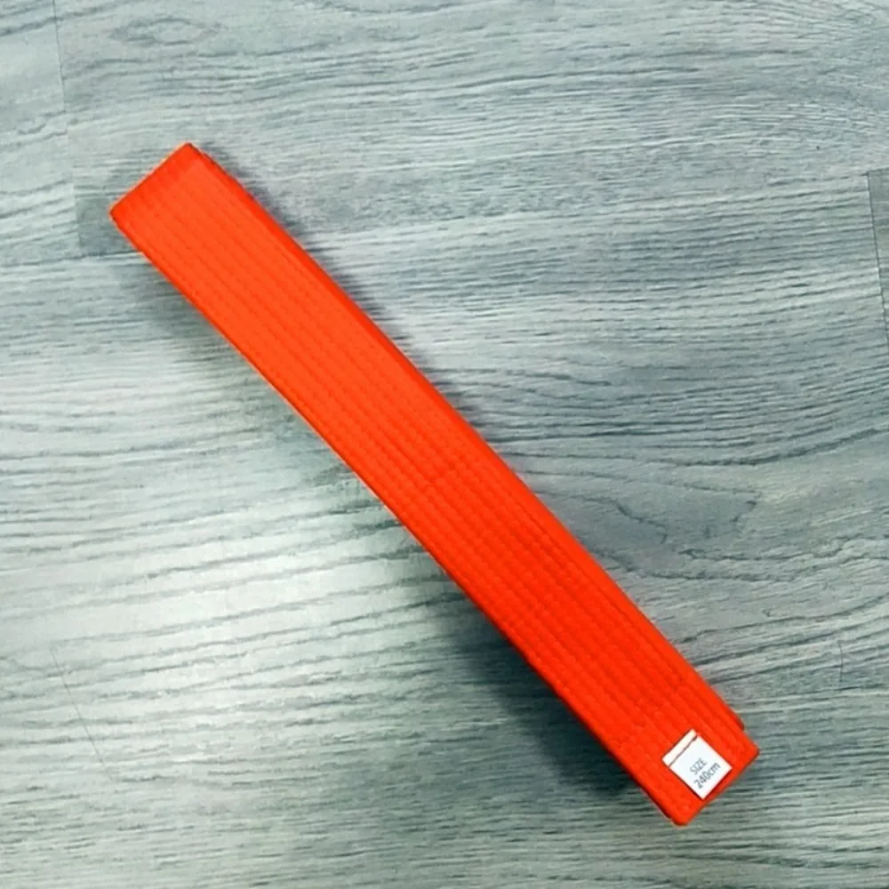 Un objeto rectangular naranja vibrante con una etiqueta colocada en una superficie gris texturizada