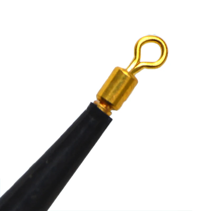 Un primer plano de un objeto negro con una pieza de metal de color dorado adherida. La pieza de metal parece ser un gancho o un anillo, posiblemente usado para asegurar o sujetar el objeto a otra cosa.
