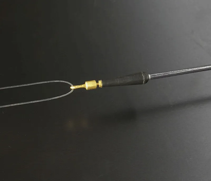 Un primer plano de una herramienta con eje metálico y mango negro. La herramienta parece tener un pequeño gancho o bucle en el extremo, que a menudo se usa para recoger objetos pequeños o para otras tareas de precisión.