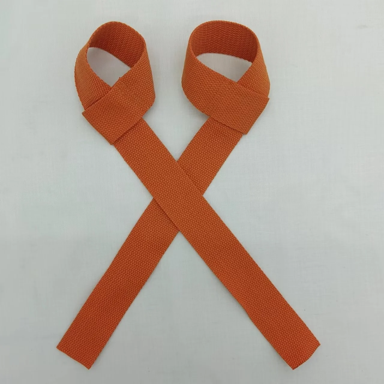 Un par de pulseras naranjas con un diseño de bucle, que se utilizan a menudo para identificación o como accesorio de moda. Se colocan planos, con los bucles hacia arriba y las bandas se cruzan entre sí para formar una X.