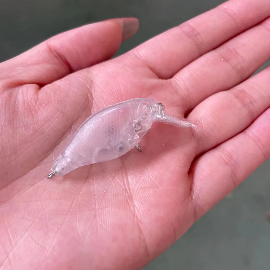 Un delicado señuelo de pesca translúcida descansa suavemente en la palma de una persona, lista para la próxima aventura