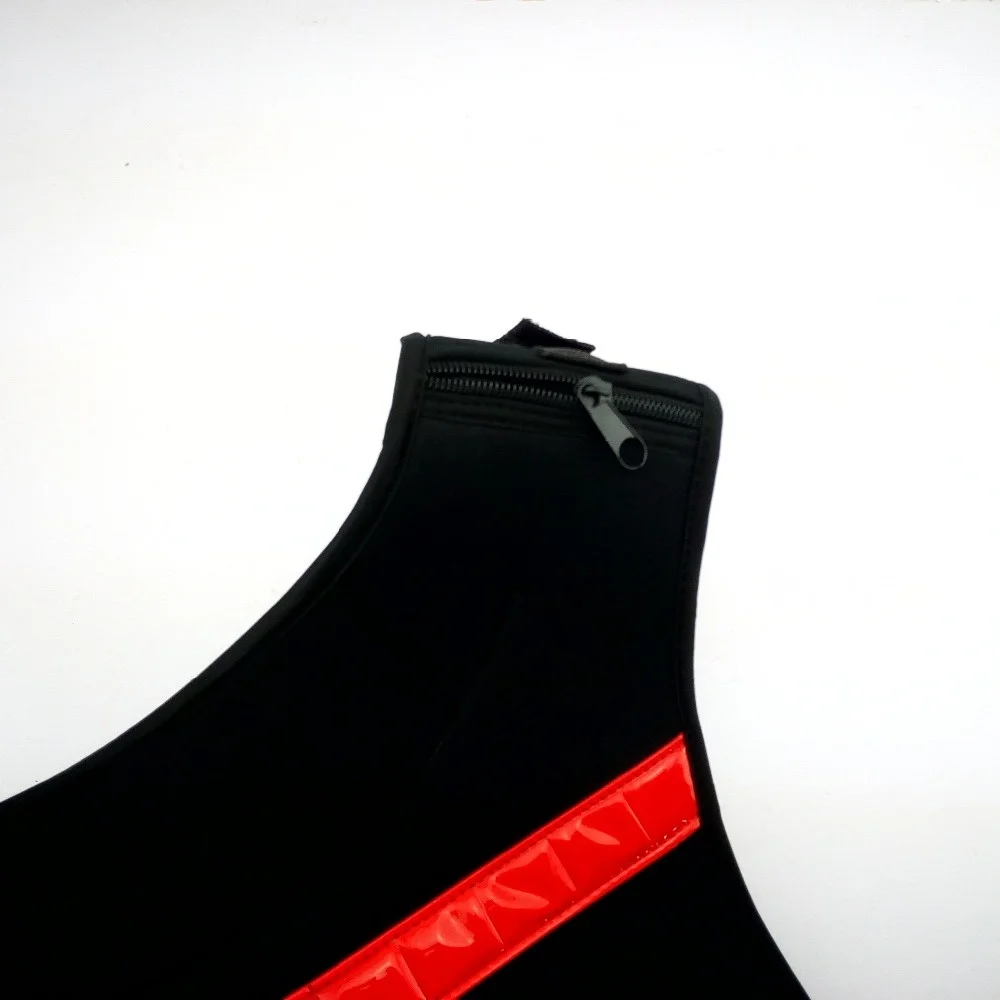 Un primer plano de un objeto negro con una franja roja a lo largo de su costado. El objeto parece ser una maleta o un bolso, como lo indican el tirador de la cremallera y la textura de la tela. La franja roja podría ser un elemento decorativo o el logo de una marca.
