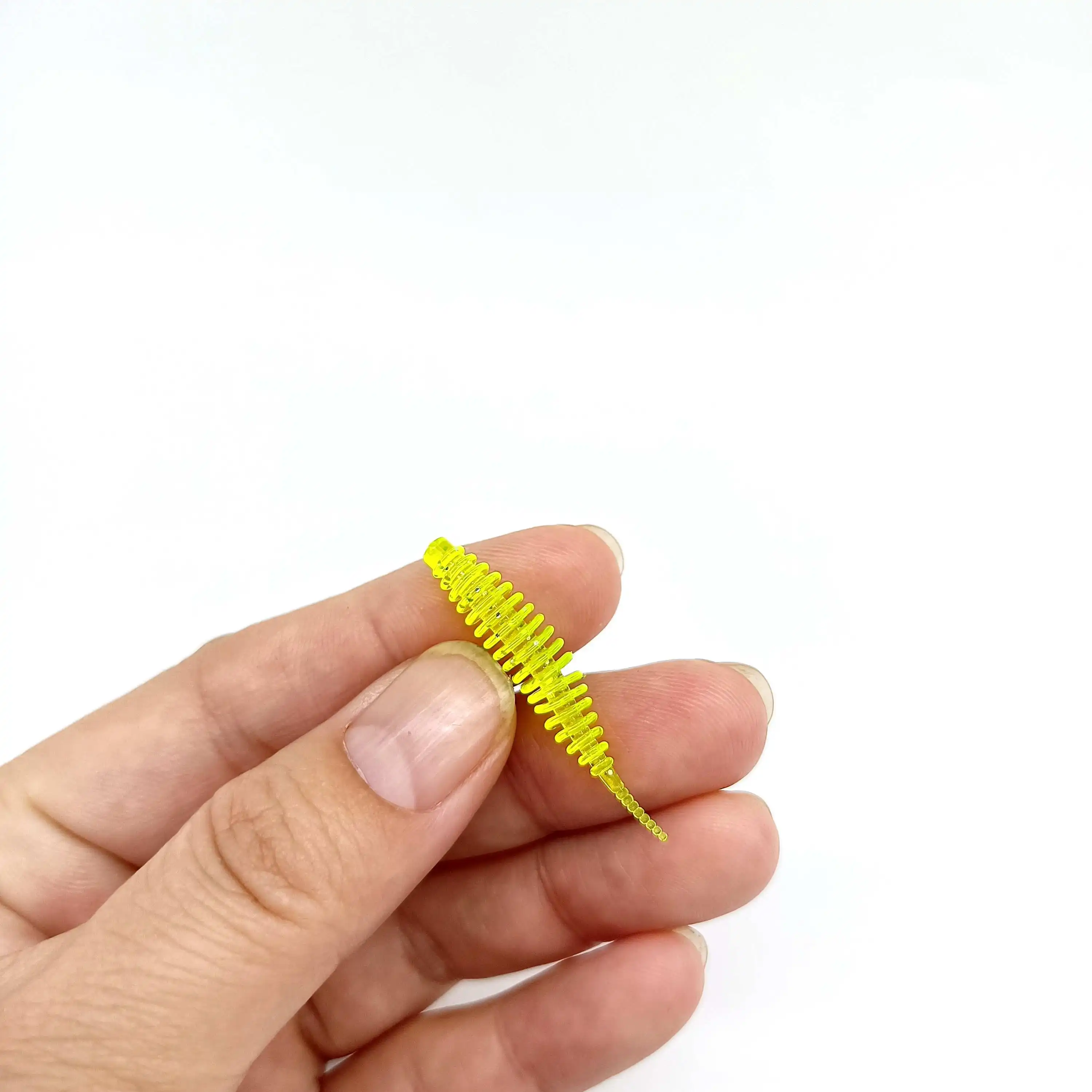 Se mantiene un pequeño objeto amarillo y texturizado que se asemeja a un gusano entre los dedos